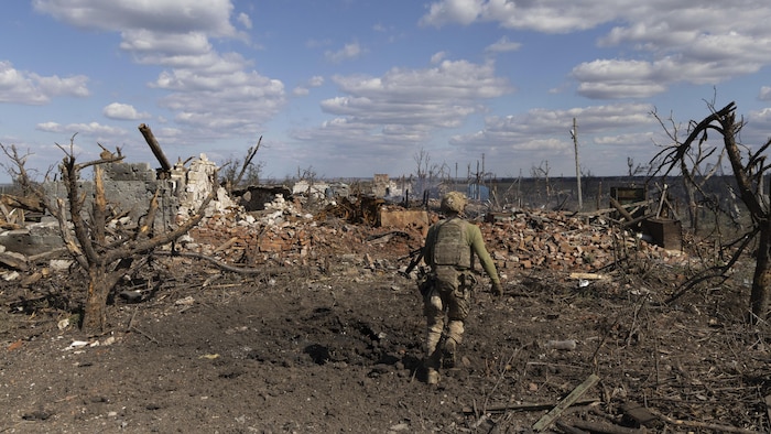 A person walks through a war-torn town.